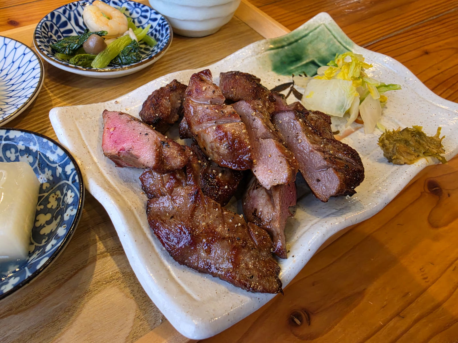 生成りの器に盛った厚切りの牛たん焼き。断面はほんのり赤く、白菜の漬物と南蛮味噌を添えて。