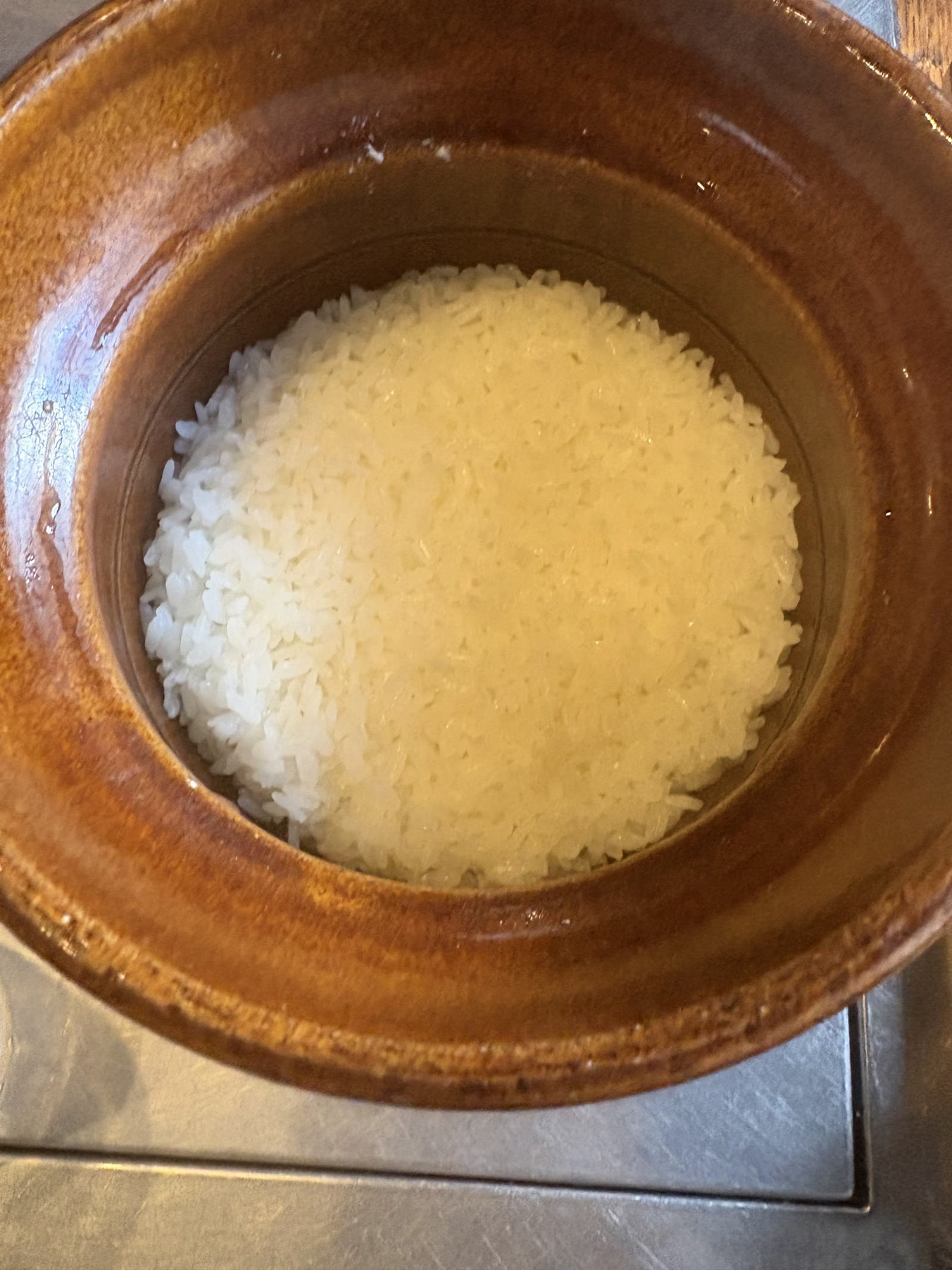 飴色の土鍋に炊き上がった白いご飯を真上から。