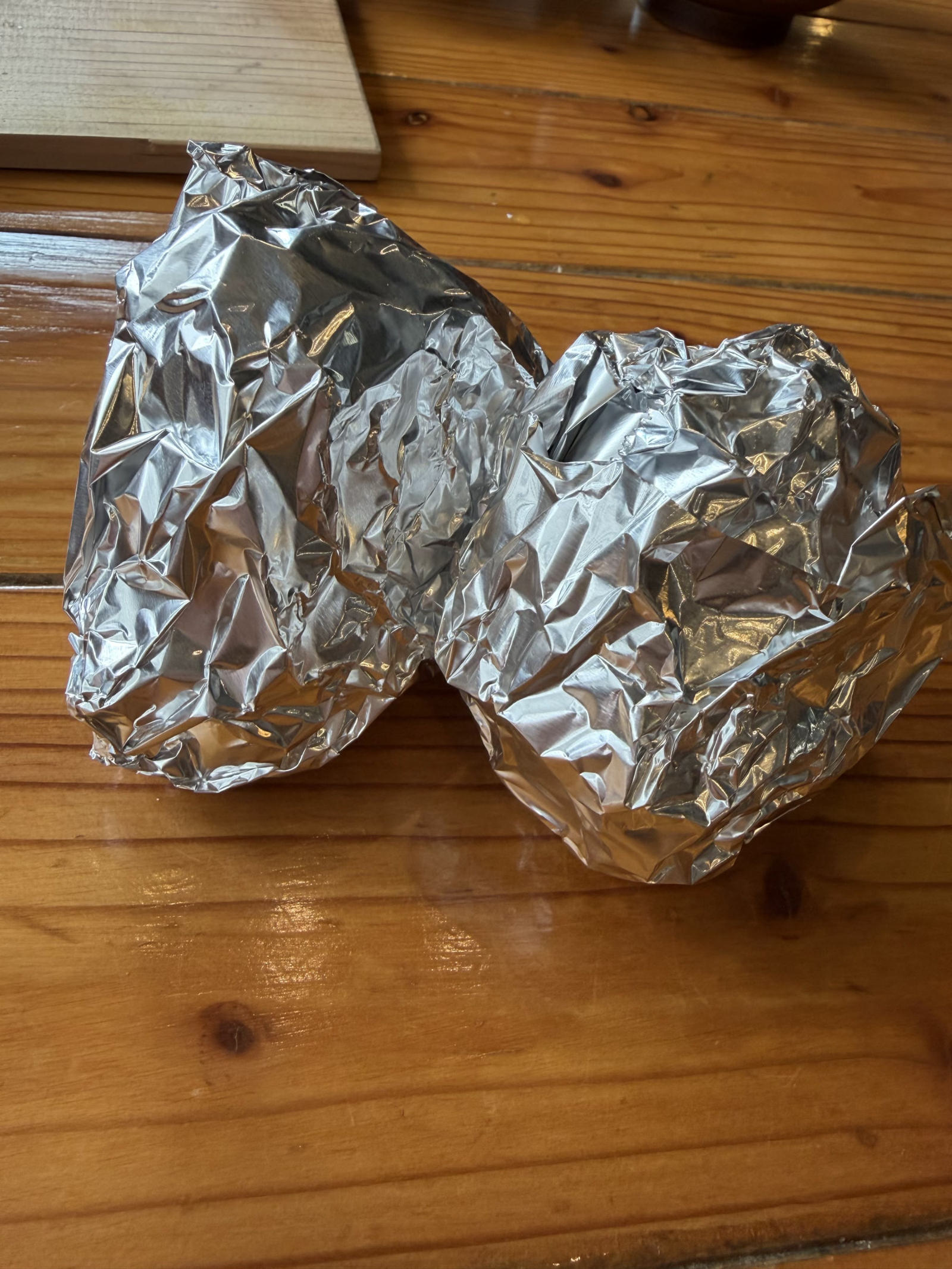 残りのご飯をホイルに包んでお持ち帰り。木のテーブルに二つ。