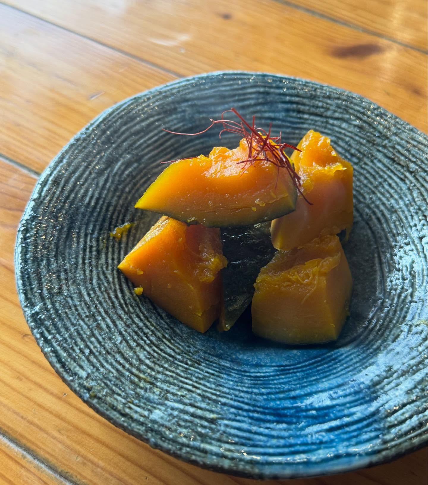青い器にかぼちゃの煮物。上に糸唐辛子。