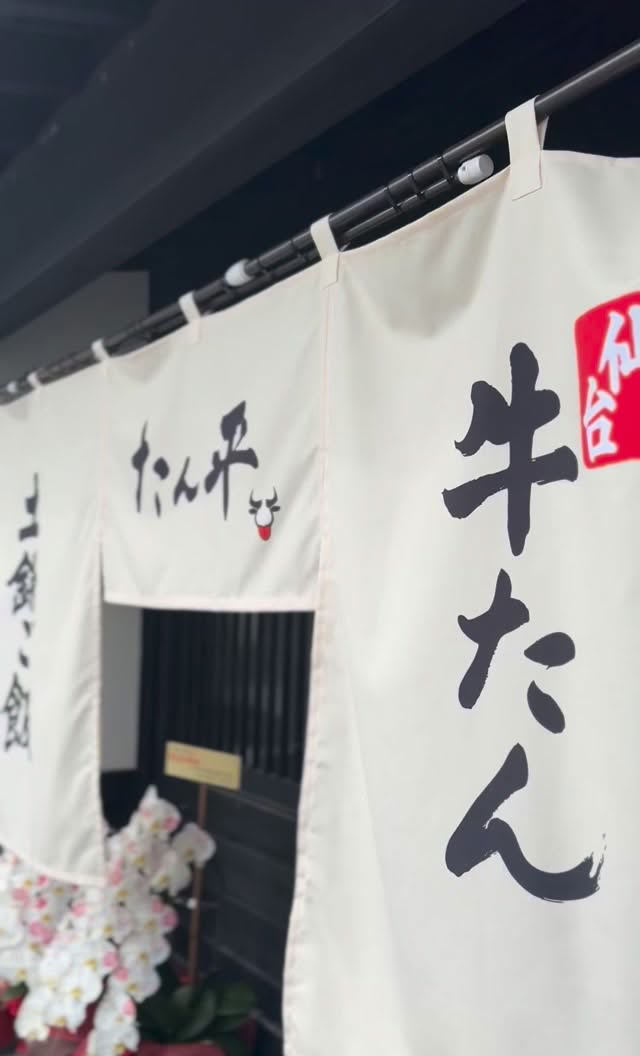 「土鍋ご飯」「たん平」「仙台 牛たん」の暖簾。入口に白とピンクの胡蝶蘭。